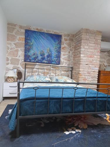 a bed in a room with a painting on the wall at jardin kapetanova kuća in Veli Iž