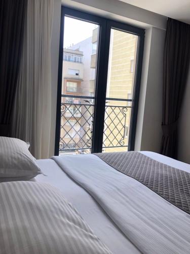 a bedroom with a bed and a large window at Qama Hotel in Pristina