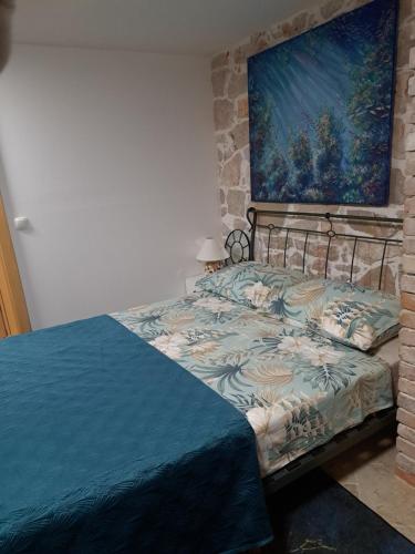 a bed in a bedroom with a painting on the wall at jardin kapetanova kuća in Veli Iž