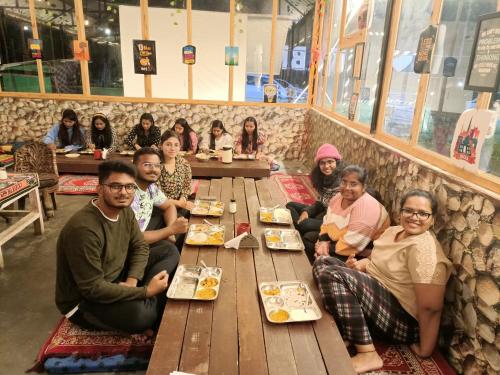 a group of people sitting at a table in a restaurant at Kabila Camp in Kasol