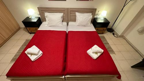 a large bed with red sheets and white pillows at Patras Palm Tree in Patra