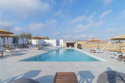 une grande piscine avec des chaises et des parasols dans l'établissement ALIRENE MYKONOS, à Panormos Mykonos