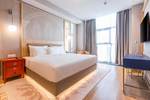 a bedroom with a large white bed and a television at Hilton Garden Inn Samarkand Sogd in Samarkand