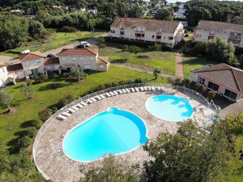 - une vue aérienne sur deux grandes piscines dans une cour dans l'établissement Appartement T2 bord de mer/piscines, à Moriani-Plage