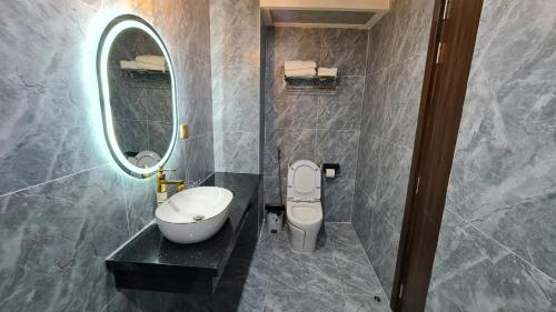 a bathroom with a toilet and a sink and a mirror at LA MIA Lakeview Hotel in Pleiku