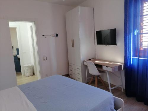 a bedroom with a bed and a desk and a television at Casa dei Mulini in Favignana