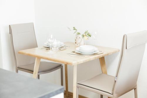 a table with two chairs and a wooden table with plates at HEIMATEL - Suiten, Apartments und Studios in Scheidegg