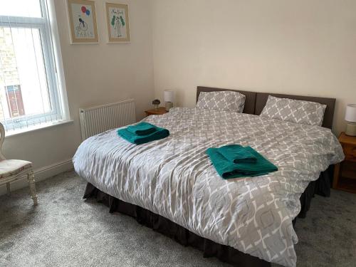 a bedroom with a bed with two green towels on it at Border cottage in Earby