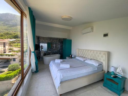 a bedroom with a bed and a tub and a window at Villa Horus in Sveti Stefan