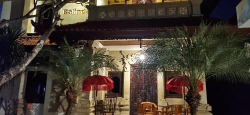 a building with palm trees in front of it at Balinda Rooms & Villa in Lovina