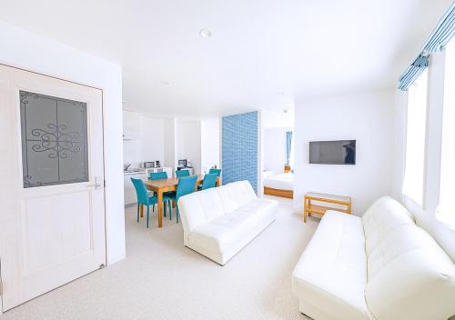 a white living room with a white couch and a table at Hotel California Miyakojima Resort in Miyako Island