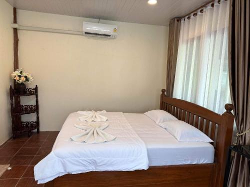 a bedroom with a bed with white sheets and a window at Buddha Raksa in Thong Nai Pan Yai