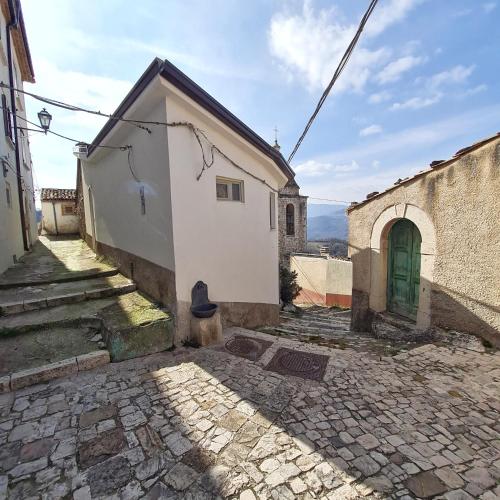 a small white building with a green door on a street at Casa vacanza Nonno Beppe in Bagnoli del Trigno