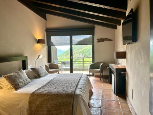 a bedroom with a bed and a large window at Hotel Rural-Spa Resguard Dels Vents in Ribes de Freser