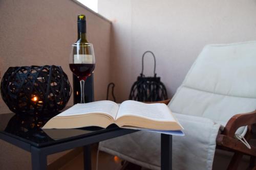een open boek op een tafel naast een fles wijn bij Apartmani Dina 2 in Posedarje
