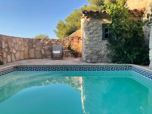 una piscina frente a una casa con una pared de piedra en L’île aux fleurs en Ventabren