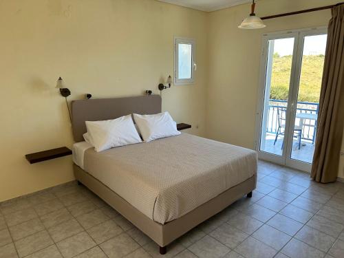 um quarto com uma cama e uma varanda em Liberatos Village em Lassi