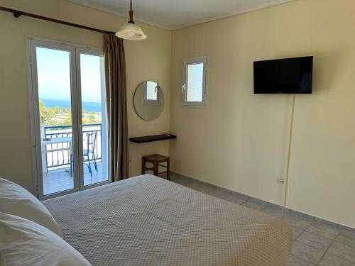 a bedroom with a bed and a television and a balcony at Liberatos Village in Lassi