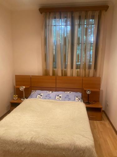 een slaapkamer met een bed en een raam met gordijnen bij Коттедж на берегу оз. Севан in Sevan