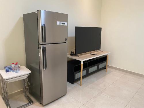 a kitchen with a refrigerator and a desk with a tv at Your apartment near Airport in Abu Dhabi