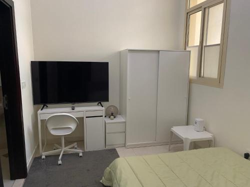 a bedroom with a television and a desk with a chair at Your Studio Near Airport and all in Abu Dhabi
