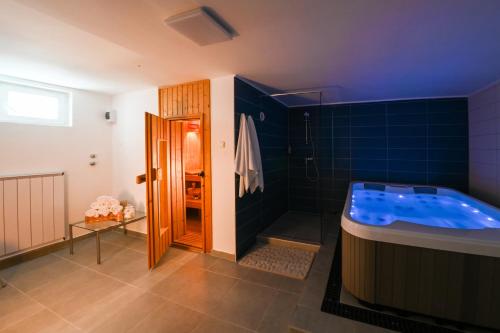 a bathroom with a tub and a shower with blue tiles at Kozmáry Vendégház in Matrafured