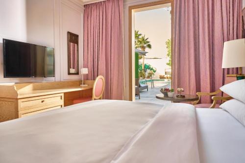 una camera con un grande letto e una televisione di Palmyard Hotel a Manama