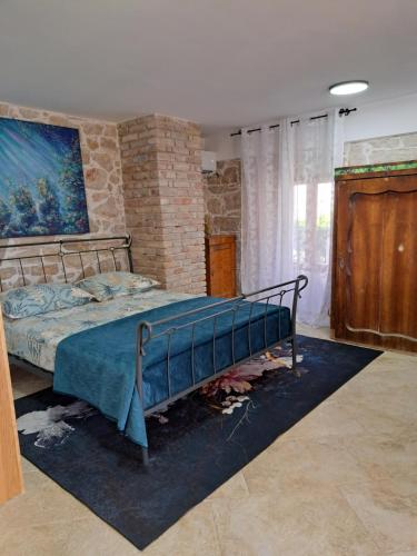 a bedroom with a bed and a brick wall at jardin kapetanova kuća in Veli Iž