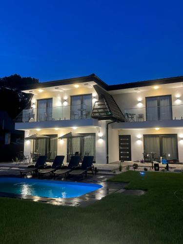 a house with chairs and a swimming pool at night at Lux apartments in Orosháza