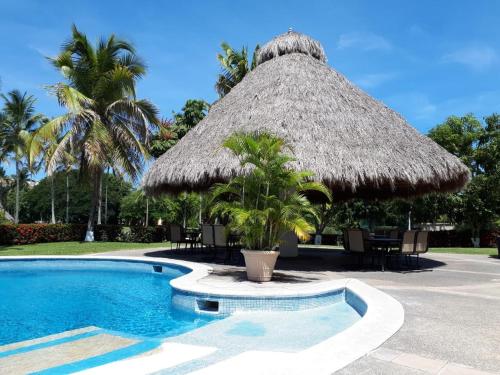 a resort swimming pool with a thatched umbrella and palm trees at marina vallarta, One bedroom condo in Puerto Vallarta