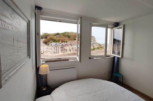Un dormitorio pequeño con una cama y dos ventanas. en Le Duplex, Vue Mer et Port, en Saint-Valéry-en-Caux