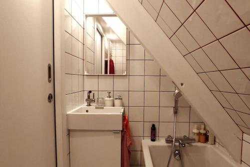 Un baño blanco con lavabo y espejo. en Le Duplex, Vue Mer et Port, en Saint-Valéry-en-Caux