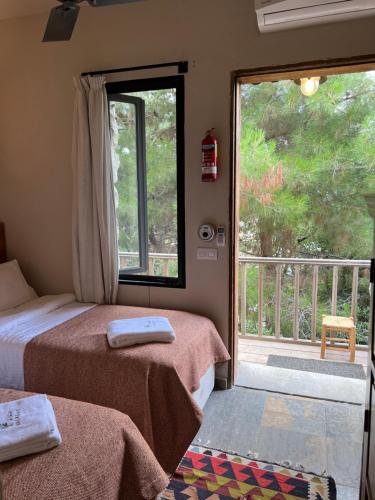 a room with two beds and a balcony with a window at Bkerzay in Baakleen