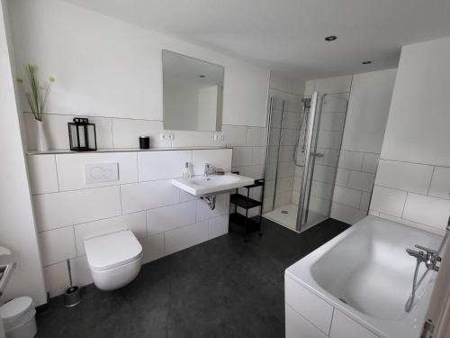 ein weißes Badezimmer mit einem WC, einem Waschbecken und einer Badewanne in der Unterkunft Ferienwohnung am Thonhopsberg in Eimke