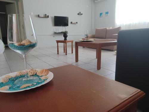 un bicchiere da vino seduto su un tavolo con un piatto di cibo di Άνετο Διαμέρισμα a Artemida
