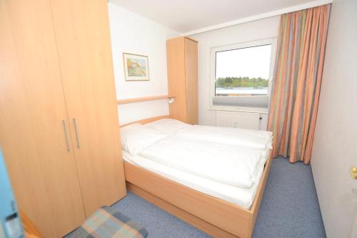 ein kleines Schlafzimmer mit einem Bett und einem Fenster in der Unterkunft Appartement 156 in Westerland