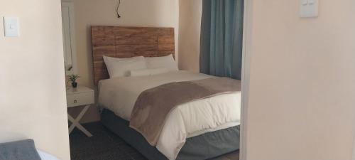 a bedroom with a bed with a wooden headboard at Seqonoka Villa Accommodation & Events Park in Berea Hills