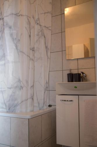 a white bathroom with a sink and a mirror at Apartmani Dina 1 in Posedarje