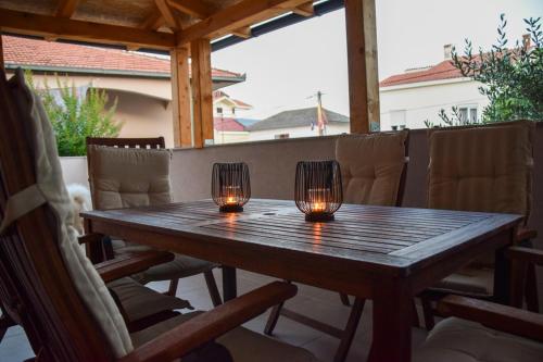 twee kaarsen op een houten tafel op een terras bij Apartmani Dina 1 in Posedarje