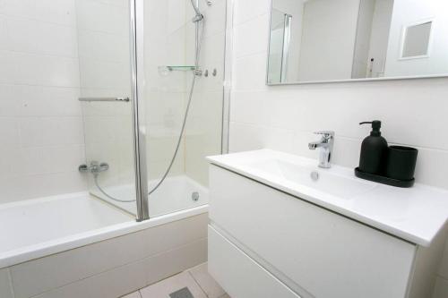 a white bathroom with a shower and a sink at Luxury 2BR Central TLV Apartment in Tel Aviv