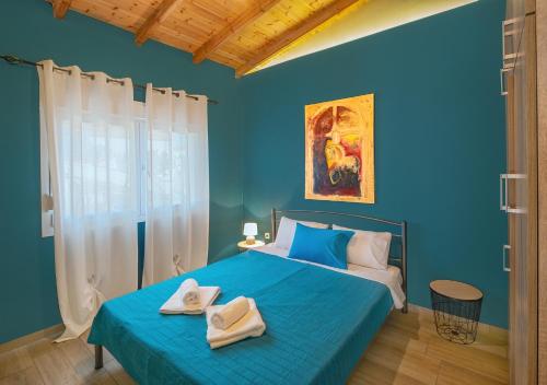 Un dormitorio azul con una cama con toallas. en Hara Apartments en Chrysoupolis