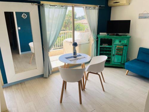 a living room with a table and chairs and a television at Studio de standing climatisé, avec piscine, proche de la mer in Fréjus
