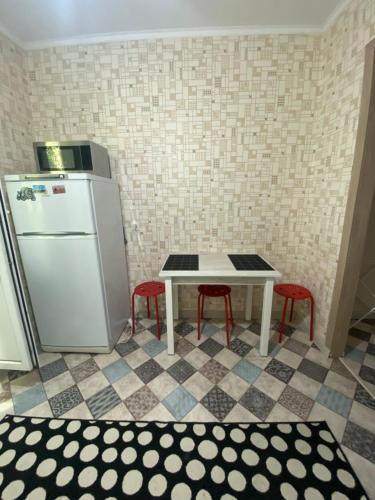 a small kitchen with a table and a refrigerator at Уютная квартира напротив Меги in Aktobe