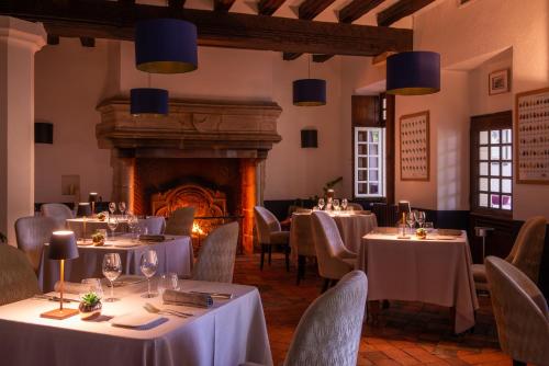 a restaurant with tables and chairs and a fireplace at Relais Des Landes in Ouchamps