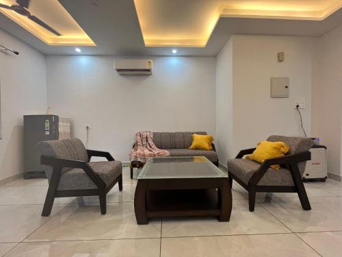 sala de estar con 2 sillas, mesa y sofá en Ananta - Rishikesh Luxurious 2BHK en Rishīkesh