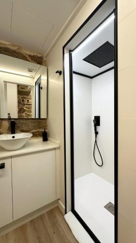 a glass shower door in a bathroom with a sink at Celanova House in Celanova