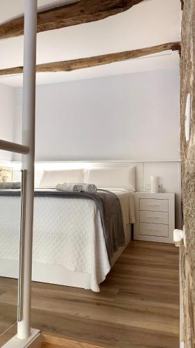 a bedroom with a white bed and a wooden floor at Celanova House in Celanova
