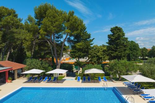 a swimming pool with chairs and umbrellas at Mediterranean Village San Antonio in Biograd na Moru