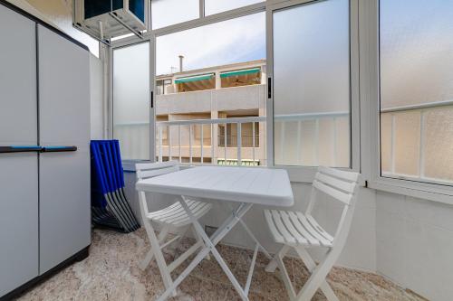 un tavolo bianco con sedie in una stanza con finestre di Calle Concordia 86, two bedroom apartment, up to 6 guests, near Del Cura beach,supermarket Mercadona and central bus station a Torrevieja