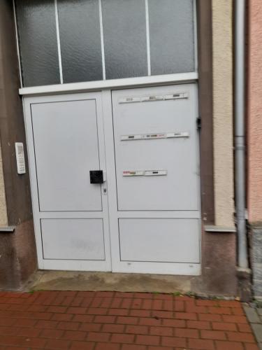 un paio di porte bianche per il garage su un edificio di Kleine Wohnung für Monteure und Dienstreisen a Zwickau